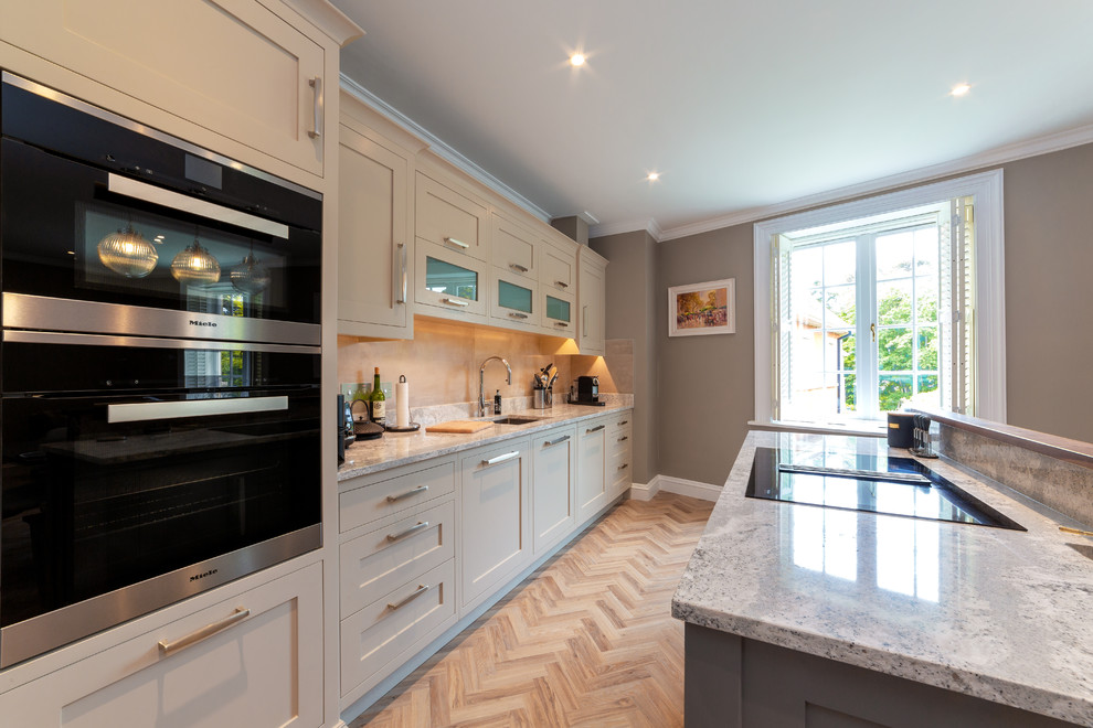 Inspiration for a timeless vinyl floor kitchen remodel in Dublin with a drop-in sink, solid surface countertops, beige backsplash, black appliances and an island