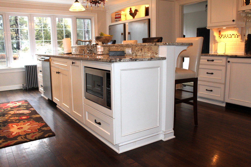 Example of a mid-sized classic u-shaped dark wood floor eat-in kitchen design in Newark with granite countertops, an undermount sink, beaded inset cabinets, white cabinets, white backsplash, subway tile backsplash, stainless steel appliances and an island