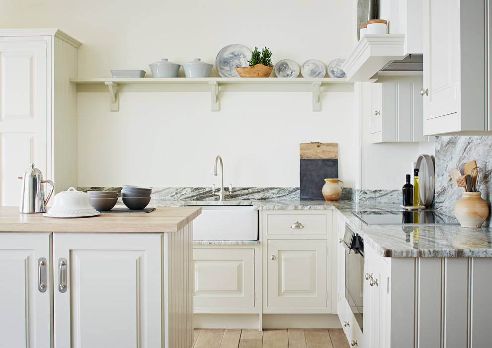 Inspiration för ett vintage l-kök, med en rustik diskho, luckor med upphöjd panel, beige skåp, svarta vitvaror, ljust trägolv och en köksö