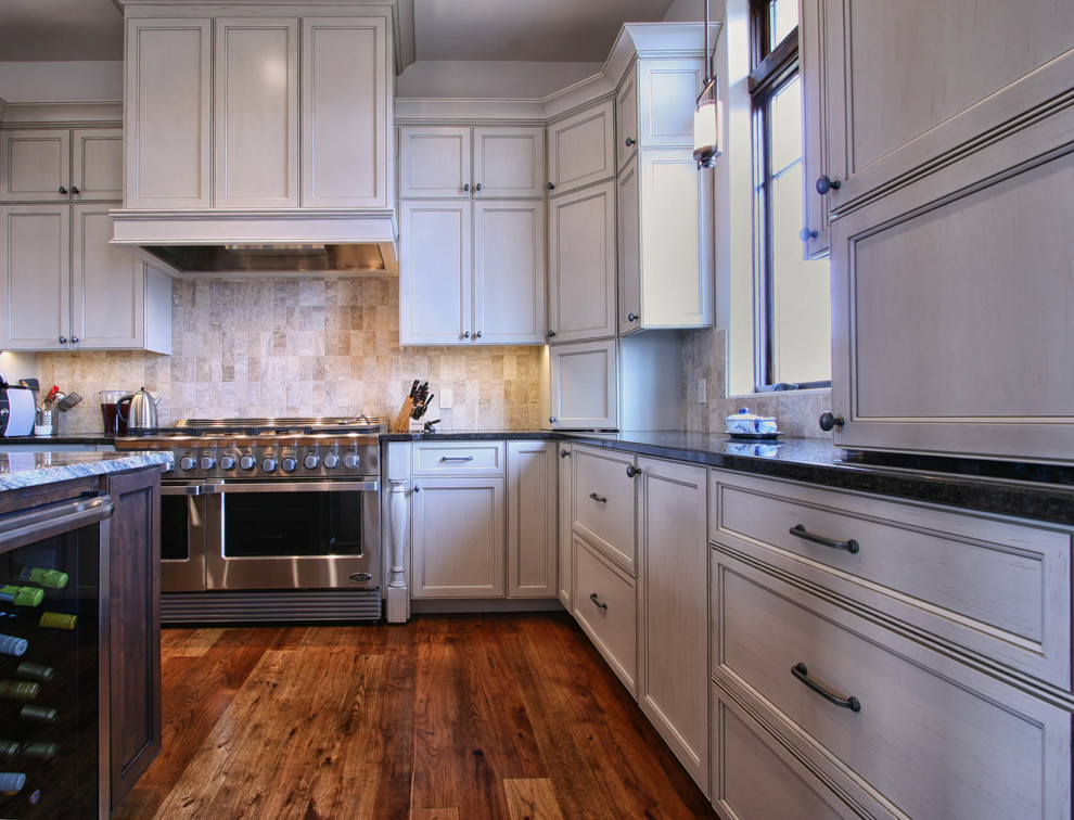 Mittelgroße Klassische Wohnküche in L-Form mit flächenbündigen Schrankfronten, Küchengeräten aus Edelstahl, braunem Holzboden, Waschbecken, Küchenrückwand in Beige und Kücheninsel in Charlotte