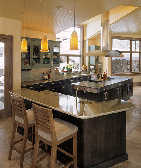 Moderne Wohnküche in L-Form mit Doppelwaschbecken, Schrankfronten im Shaker-Stil, dunklen Holzschränken, Edelstahl-Arbeitsplatte, Küchenrückwand in Grau, Küchengeräten aus Edelstahl, Travertin und Kücheninsel in Denver