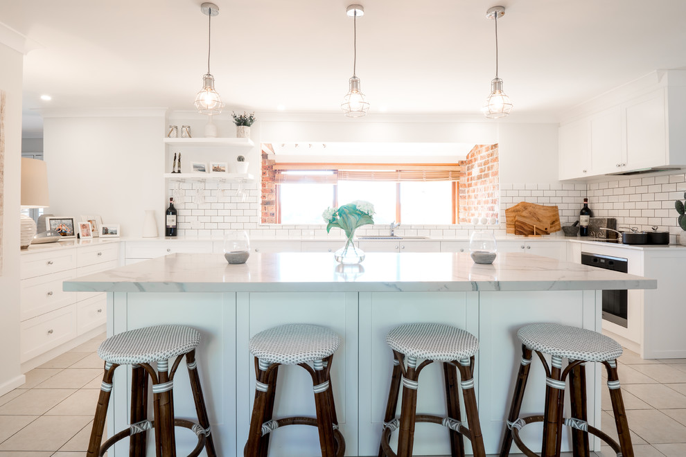 This is an example of a large contemporary u-shaped kitchen/diner in Sydney with a submerged sink, shaker cabinets, white cabinets, engineered stone countertops, white splashback, metro tiled splashback, stainless steel appliances, terracotta flooring, an island, white floors and white worktops.