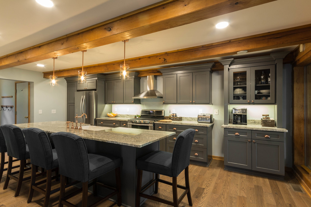 Bild på ett stort vintage linjärt kök och matrum, med en rustik diskho, skåp i shakerstil, grå skåp, granitbänkskiva, vitt stänkskydd, stänkskydd i sten, rostfria vitvaror, mellanmörkt trägolv, en köksö och grått golv