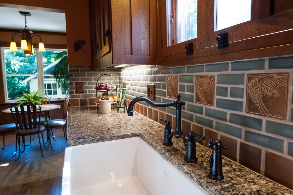 Photo of a small traditional l-shaped enclosed kitchen in Detroit with a belfast sink, beaded cabinets, medium wood cabinets, engineered stone countertops, grey splashback, metro tiled splashback, stainless steel appliances, dark hardwood flooring and no island.