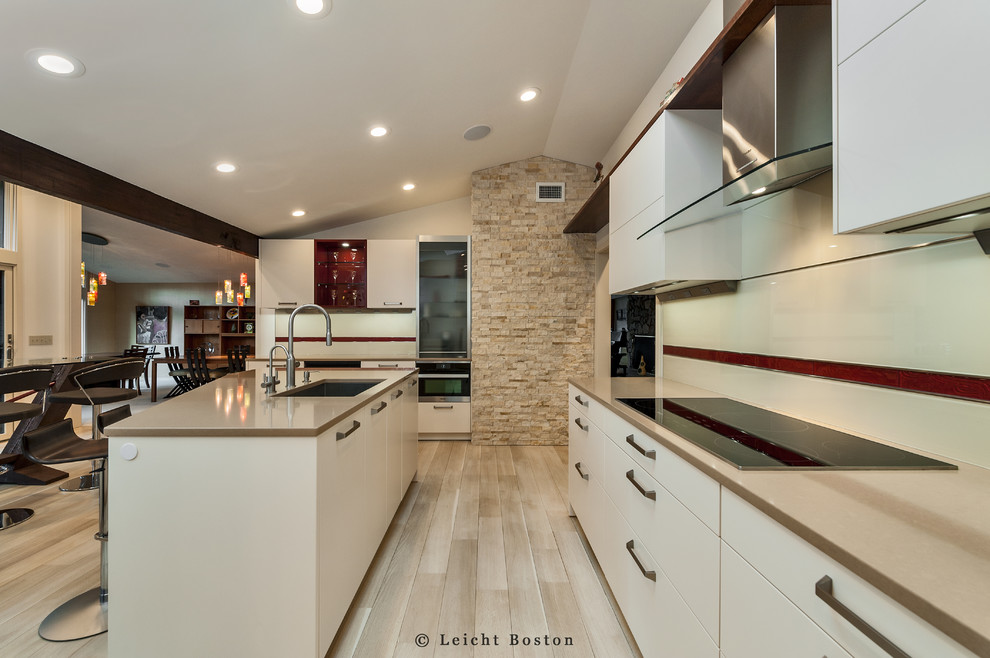 Example of a huge trendy u-shaped light wood floor eat-in kitchen design in Boston with an undermount sink, flat-panel cabinets, white cabinets, quartz countertops, white backsplash, glass sheet backsplash, white appliances and an island