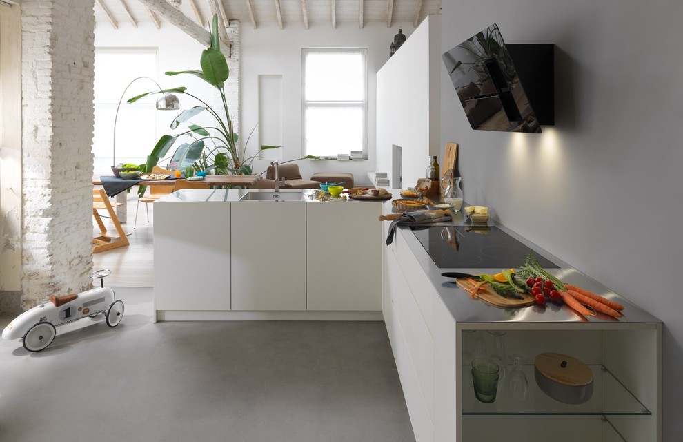 Immagine di una cucina a L minimal con lavello sottopiano, ante lisce, ante bianche, top in acciaio inossidabile, paraspruzzi grigio, pavimento in cemento, pavimento grigio e top grigio