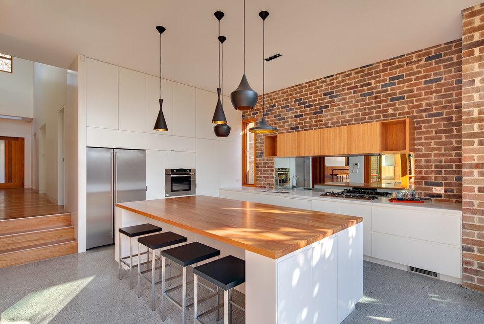 シドニーにあるコンテンポラリースタイルのおしゃれなL型キッチン (フラットパネル扉のキャビネット、白いキャビネット、木材カウンター、シルバーの調理設備) の写真