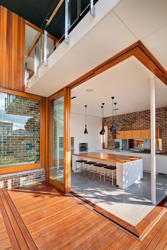Moderne Küchenbar in L-Form mit flächenbündigen Schrankfronten, weißen Schränken, Arbeitsplatte aus Holz und Küchengeräten aus Edelstahl in Sydney