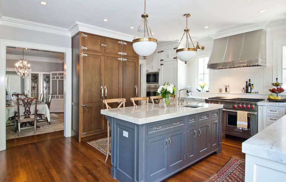 Diseño de cocina clásica con armarios con paneles empotrados, puertas de armario azules, salpicadero blanco, electrodomésticos con paneles y encimera de cuarcita