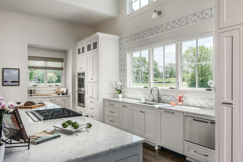 Example of a large transitional l-shaped dark wood floor open concept kitchen design in Nashville with a single-bowl sink, shaker cabinets, white cabinets, quartz countertops, white backsplash, porcelain backsplash, paneled appliances, an island and white countertops