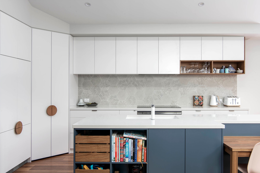 Exempel på ett mellanstort modernt vit vitt kök, med en undermonterad diskho, bänkskiva i kvarts, grått stänkskydd, stänkskydd i keramik, mellanmörkt trägolv, en köksö, släta luckor, vita skåp och brunt golv