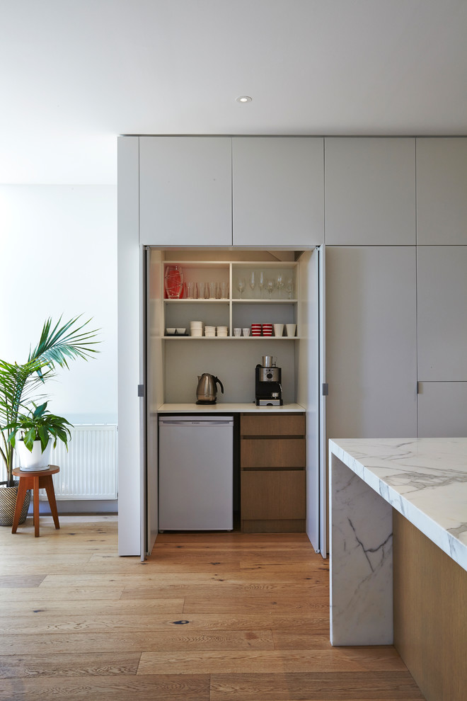 Inspiration pour une cuisine linéaire minimaliste avec plan de travail en marbre, un sol en bois brun et îlot.