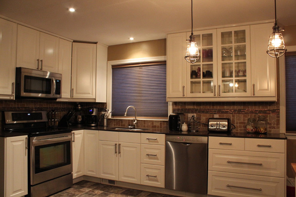 This is an example of a traditional l-shaped kitchen in Vancouver with raised-panel cabinets, white cabinets, brown splashback, stone tiled splashback, stainless steel appliances and a double-bowl sink.