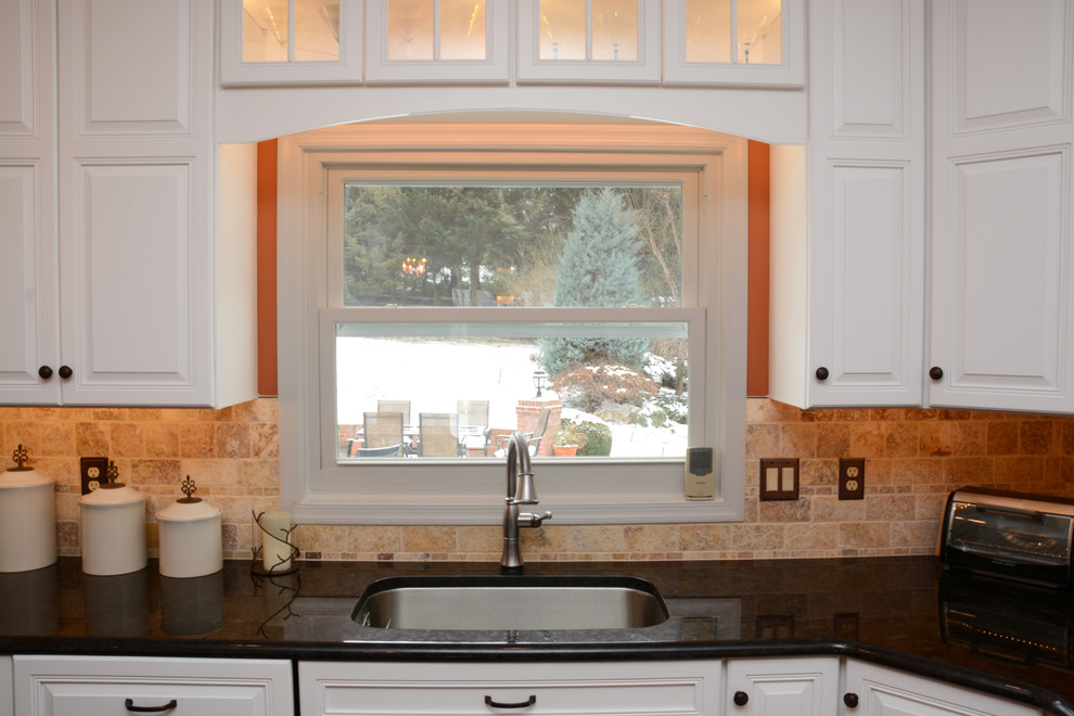 Klassisk inredning av ett stort kök, med en enkel diskho, luckor med upphöjd panel, vita skåp, granitbänkskiva, beige stänkskydd, rostfria vitvaror, mellanmörkt trägolv och en köksö