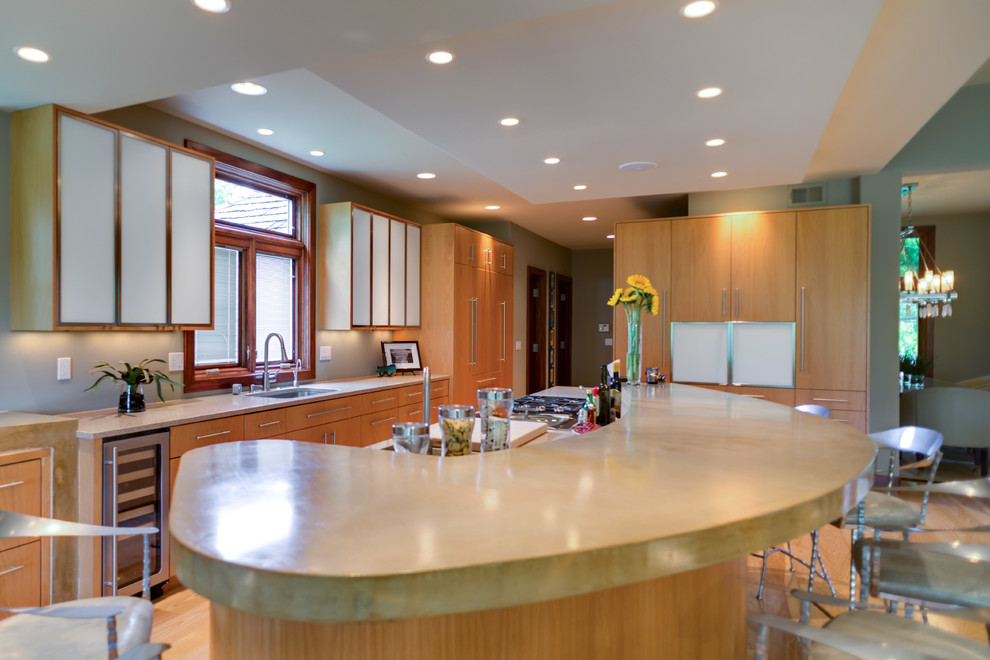 Bild på ett stort funkis linjärt kök med öppen planlösning, med ljust trägolv, en enkel diskho, släta luckor, skåp i ljust trä, rostfria vitvaror och en köksö