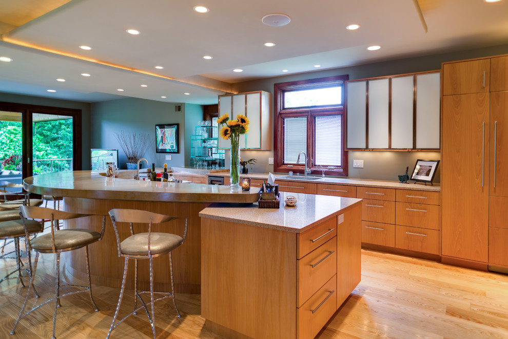 Photo of a large contemporary single-wall open plan kitchen in Kansas City with a single-bowl sink, flat-panel cabinets, light wood cabinets, stainless steel appliances, light hardwood flooring and an island.