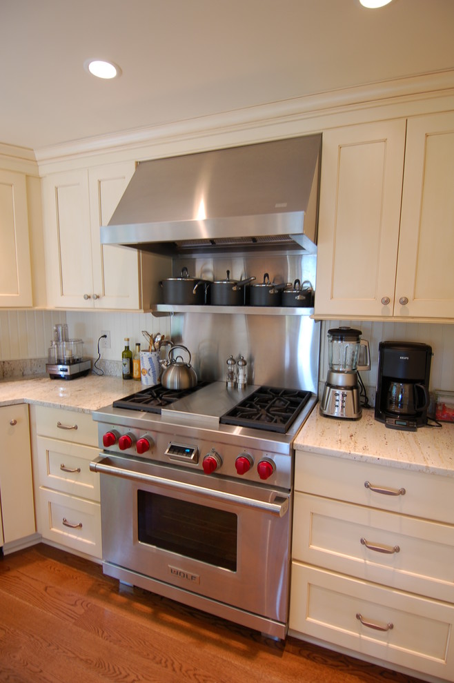 Mittelgroße Maritime Küche mit Landhausspüle, Schrankfronten mit vertiefter Füllung, gelben Schränken, Granit-Arbeitsplatte, Küchenrückwand in Weiß, braunem Holzboden und Kücheninsel in Boston