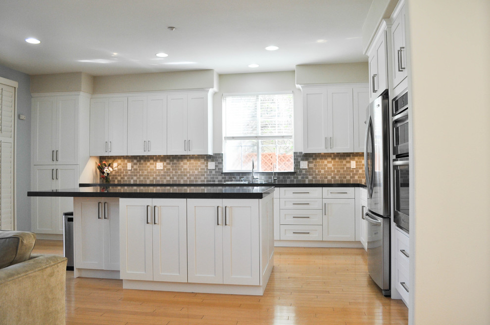 Large transitional l-shaped light wood floor eat-in kitchen photo in San Francisco with an undermount sink, shaker cabinets, white cabinets, quartzite countertops, gray backsplash, ceramic backsplash, stainless steel appliances and an island