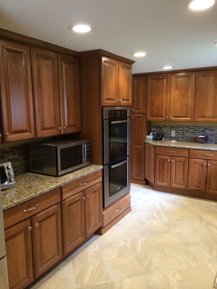 Mid-sized arts and crafts u-shaped terrazzo floor kitchen pantry photo in Boston with raised-panel cabinets, medium tone wood cabinets, granite countertops, brown backsplash, stainless steel appliances and a peninsula