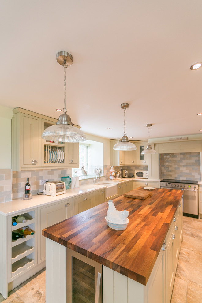 Photo of a medium sized rural l-shaped kitchen/diner in Other with a belfast sink, shaker cabinets, green cabinets, wood worktops, multi-coloured splashback, stone tiled splashback, stainless steel appliances, ceramic flooring and an island.