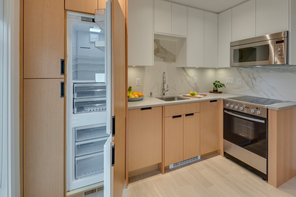 This is an example of a medium sized contemporary l-shaped open plan kitchen in Vancouver with a submerged sink, flat-panel cabinets, light wood cabinets, concrete worktops, grey splashback, stone slab splashback, integrated appliances, light hardwood flooring, no island and beige floors.