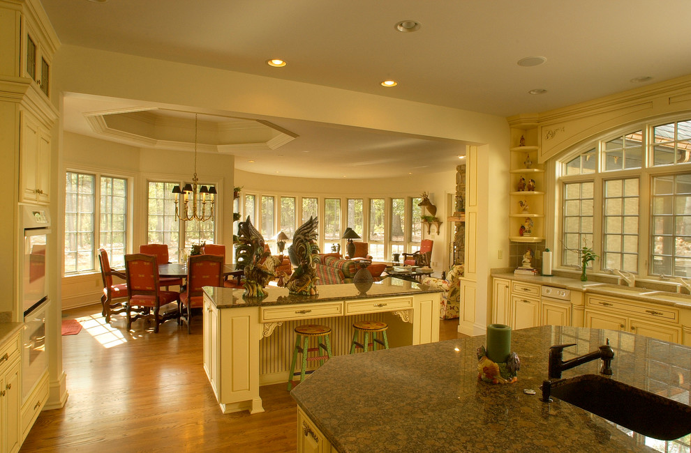 Esempio di un'ampia cucina classica con pavimento in legno massello medio, pavimento marrone, lavello a doppia vasca, ante bianche, top in granito, elettrodomestici bianchi e 2 o più isole
