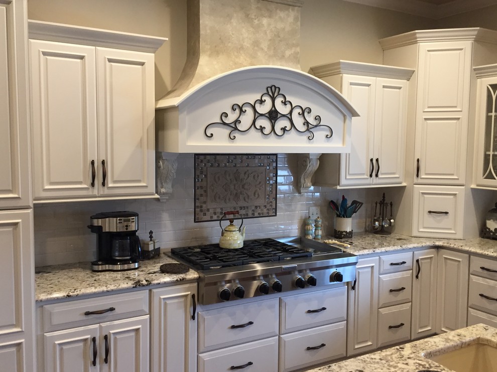 Bild på ett mycket stort vintage kök, med en undermonterad diskho, luckor med upphöjd panel, vita skåp, granitbänkskiva, vitt stänkskydd, rostfria vitvaror och flera köksöar
