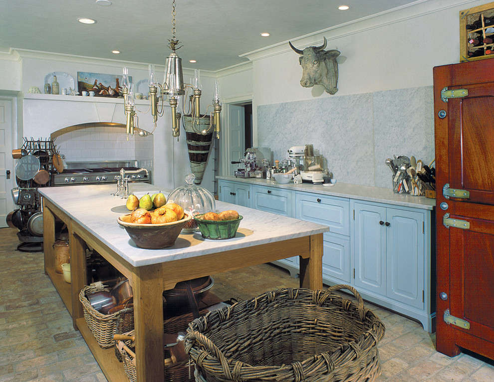 Kitchen - french country brick floor kitchen idea in Philadelphia with marble countertops, raised-panel cabinets, blue cabinets, white backsplash and stone slab backsplash