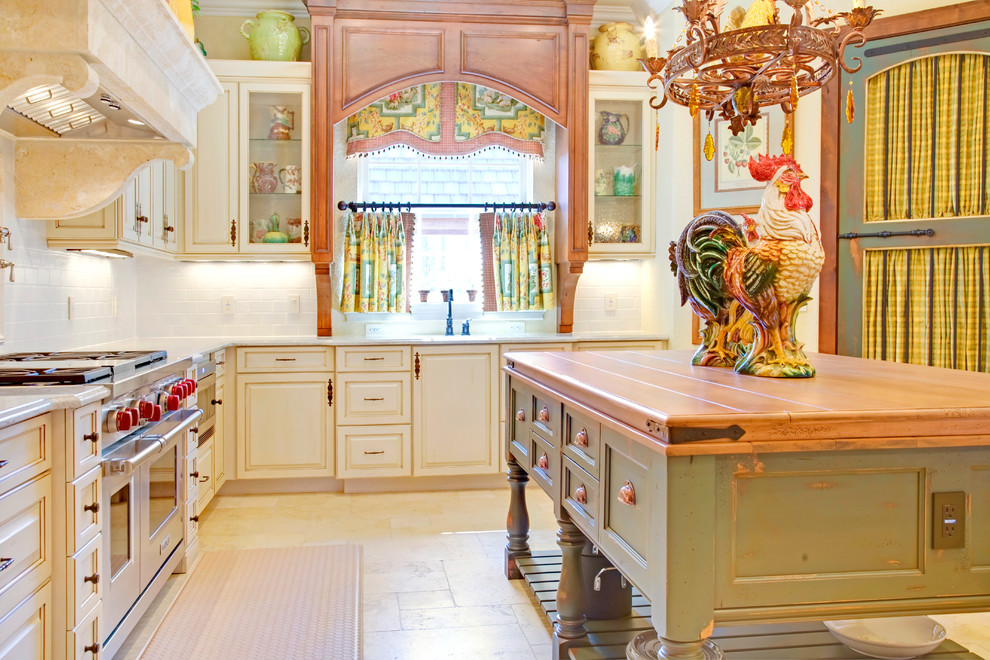 Elegant kitchen photo in Orlando with wood countertops, raised-panel cabinets, distressed cabinets, white backsplash, subway tile backsplash and stainless steel appliances