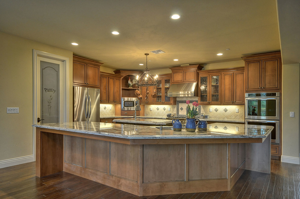 Exempel på ett amerikanskt kök, med bruna skåp, granitbänkskiva, vitt stänkskydd, stänkskydd i keramik, rostfria vitvaror och en köksö