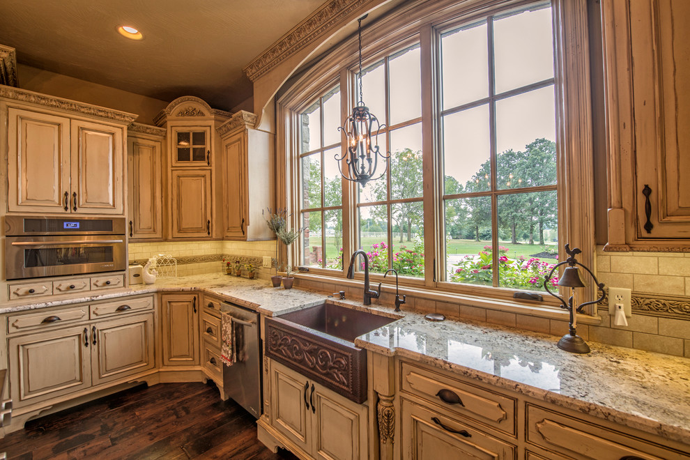 Large french country u-shaped dark wood floor eat-in kitchen photo in Other with a farmhouse sink, raised-panel cabinets, distressed cabinets, granite countertops, beige backsplash, ceramic backsplash, stainless steel appliances and an island