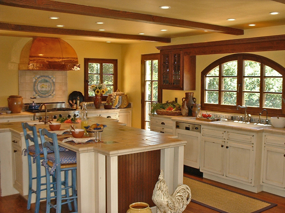 Exempel på ett stort klassiskt kök, med en undermonterad diskho, luckor med infälld panel, skåp i slitet trä, kaklad bänkskiva, flerfärgad stänkskydd, stänkskydd i keramik, integrerade vitvaror, mellanmörkt trägolv och en köksö