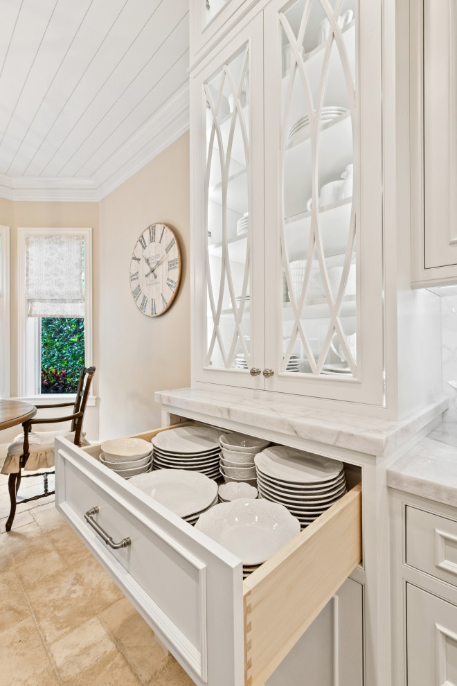 Idéer för att renovera ett mellanstort vit vitt kök, med en undermonterad diskho, luckor med profilerade fronter, vita skåp, bänkskiva i kvartsit, vitt stänkskydd, stänkskydd i marmor, integrerade vitvaror, kalkstensgolv, en köksö och beiget golv