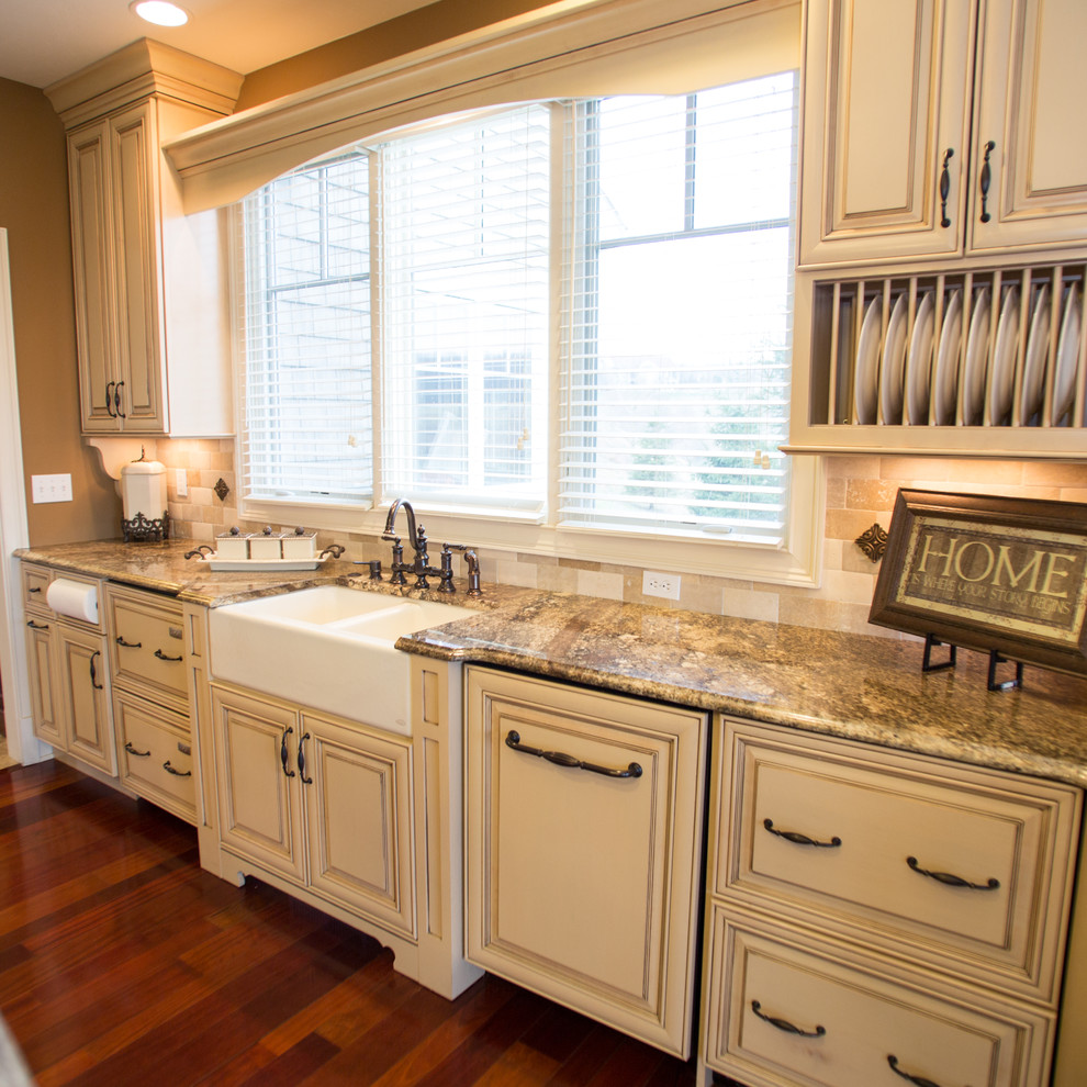 Example of a large classic medium tone wood floor eat-in kitchen design in Cleveland with a farmhouse sink, raised-panel cabinets, beige cabinets, granite countertops, beige backsplash, subway tile backsplash, stainless steel appliances and an island