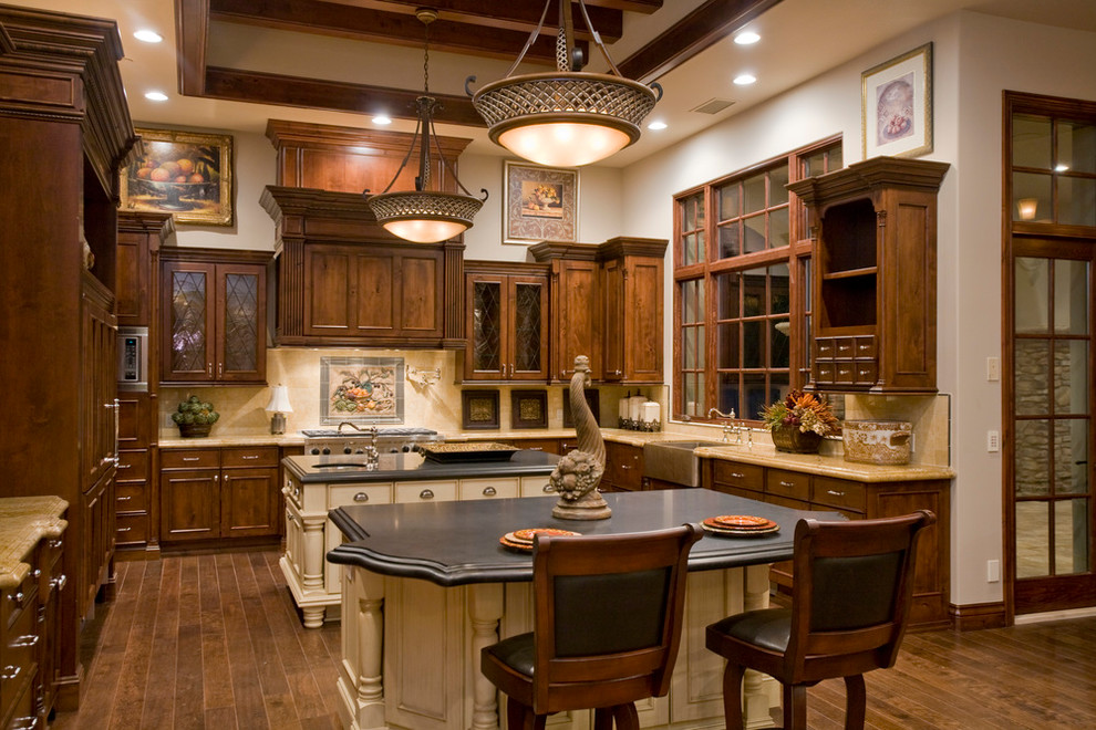 Bild på ett u-kök, med en rustik diskho, luckor med infälld panel, skåp i mörkt trä, beige stänkskydd, integrerade vitvaror, mörkt trägolv, flera köksöar och stänkskydd i keramik