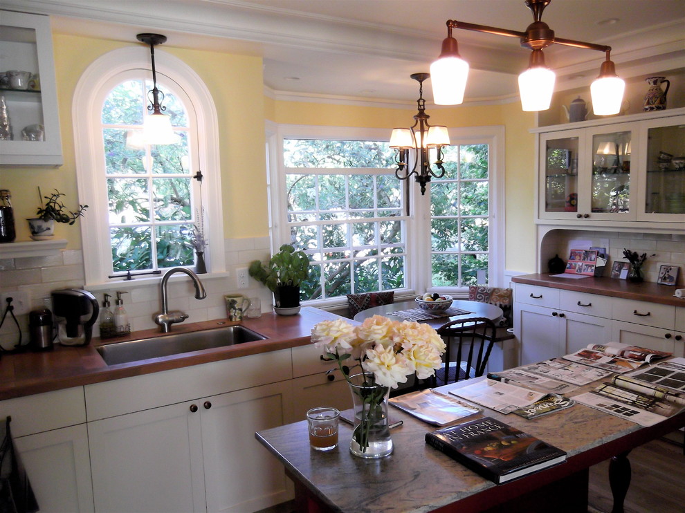 Example of a mid-sized tuscan eat-in kitchen design in Portland with an undermount sink, shaker cabinets, white cabinets, tile countertops, beige backsplash, ceramic backsplash, stainless steel appliances and two islands