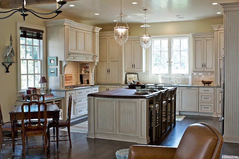 Exempel på ett stort lantligt brun brunt kök, med en köksö, en undermonterad diskho, luckor med infälld panel, skåp i slitet trä, träbänkskiva, beige stänkskydd, stänkskydd i glaskakel och rostfria vitvaror