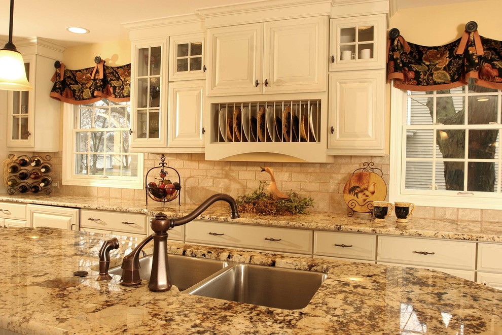 Example of a large french country l-shaped eat-in kitchen design in Chicago with a double-bowl sink, raised-panel cabinets, white cabinets, granite countertops, white backsplash, paneled appliances and an island