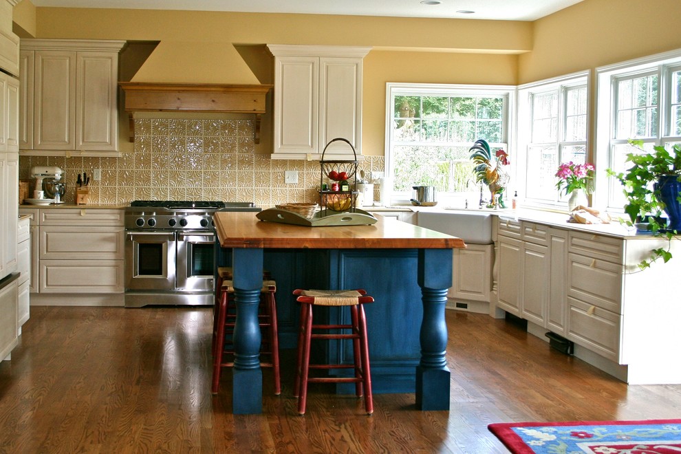 Foto på ett avskilt vintage u-kök, med en rustik diskho, träbänkskiva, luckor med upphöjd panel, gult stänkskydd, rostfria vitvaror, vita skåp, stänkskydd i keramik och mellanmörkt trägolv