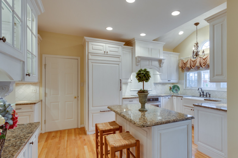 Inspiration for a timeless l-shaped eat-in kitchen remodel in DC Metro with raised-panel cabinets, white cabinets, quartz countertops, white backsplash and stainless steel appliances