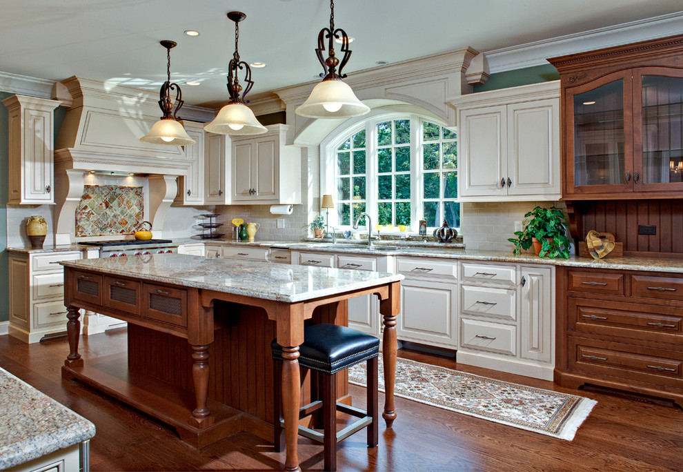 Exempel på ett stort klassiskt kök, med en dubbel diskho, luckor med infälld panel, vita skåp, granitbänkskiva, beige stänkskydd, stänkskydd i tunnelbanekakel, rostfria vitvaror och mellanmörkt trägolv