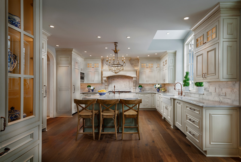Inspiration for a large transitional u-shaped dark wood floor enclosed kitchen remodel in Chicago with a farmhouse sink, raised-panel cabinets, beige cabinets, white backsplash, paneled appliances, an island and quartz countertops