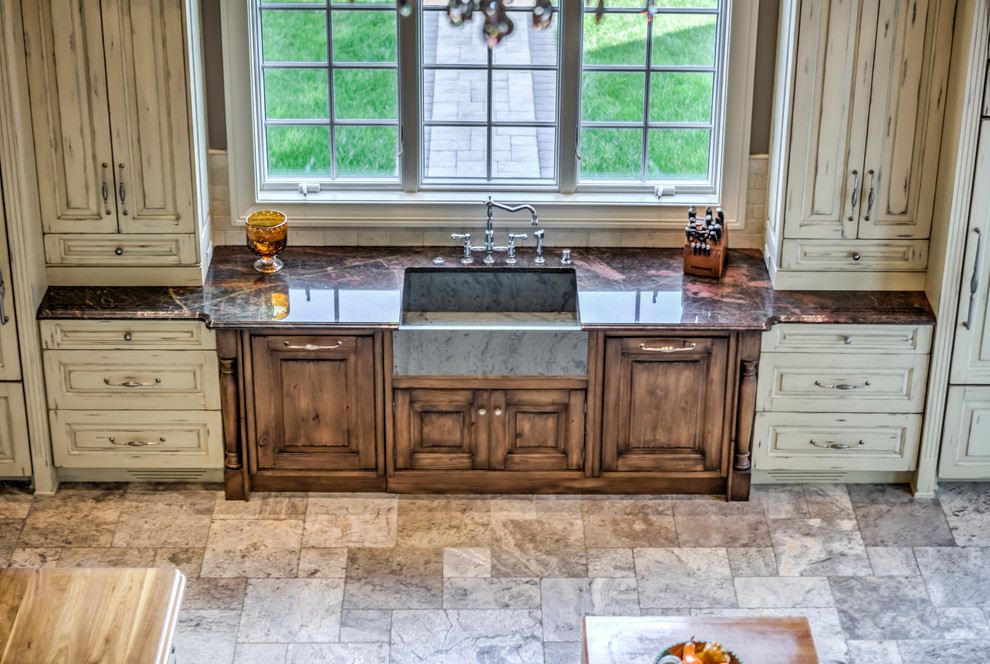 Inspiration for a huge cottage galley travertine floor eat-in kitchen remodel in Philadelphia with a farmhouse sink, raised-panel cabinets, distressed cabinets, granite countertops, beige backsplash, subway tile backsplash, paneled appliances and two islands