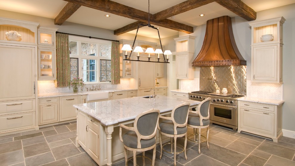 Kitchen - french country l-shaped kitchen idea in Houston with a farmhouse sink, raised-panel cabinets, beige cabinets, metallic backsplash, stainless steel appliances and an island