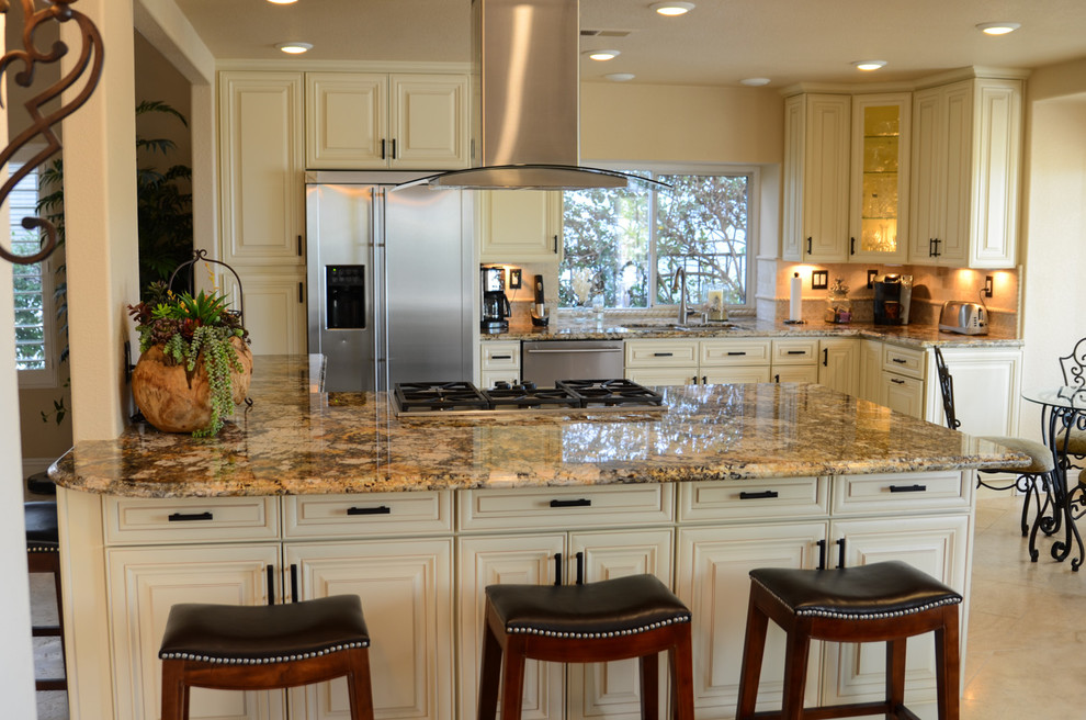 This is an example of a large classic u-shaped open plan kitchen in Tampa with a double-bowl sink, raised-panel cabinets, white cabinets, granite worktops, beige splashback, stone tiled splashback, stainless steel appliances, travertine flooring and an island.