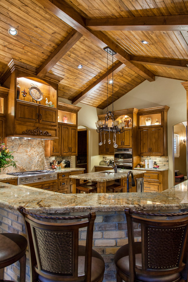 Example of a large cottage l-shaped porcelain tile eat-in kitchen design in Houston with medium tone wood cabinets, granite countertops, stainless steel appliances, a farmhouse sink, raised-panel cabinets, an island, beige backsplash and brick backsplash