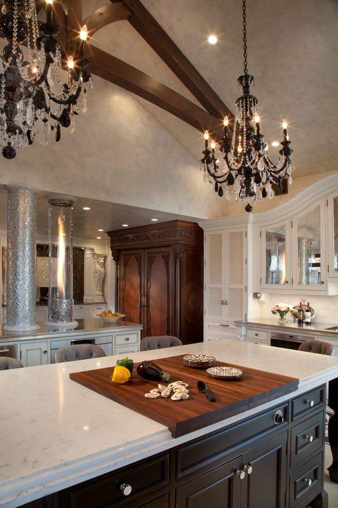 Bild på ett stort vintage grå grått kök och matrum, med en undermonterad diskho, luckor med profilerade fronter, beige skåp, vitt stänkskydd, stänkskydd i marmor, kalkstensgolv, flera köksöar och beiget golv