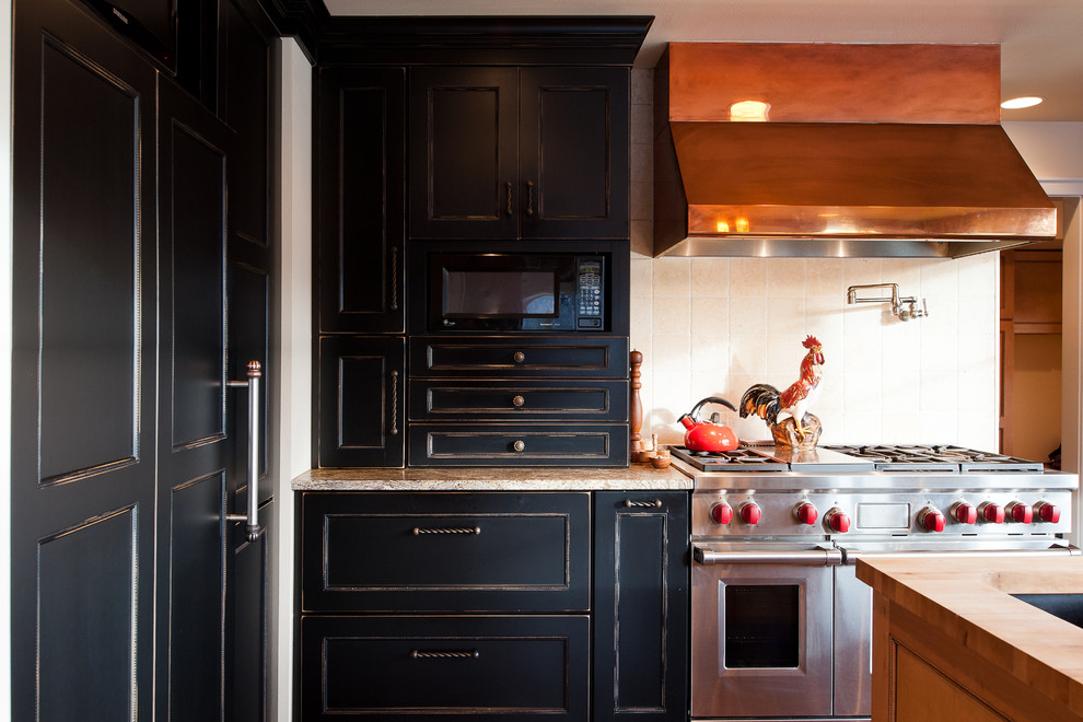 Exempel på ett avskilt, stort lantligt u-kök, med luckor med infälld panel, träbänkskiva, rostfria vitvaror, en köksö, en undermonterad diskho, svarta skåp, beige stänkskydd, stänkskydd i keramik och mörkt trägolv
