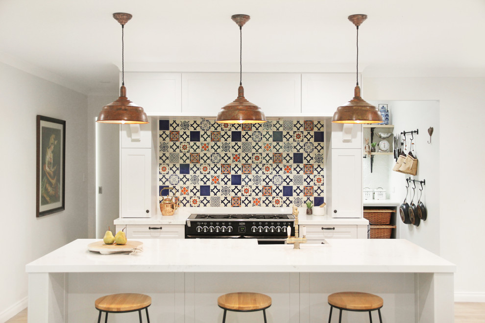 Klassische Küche mit Schrankfronten im Shaker-Stil, weißen Schränken, bunter Rückwand, schwarzen Elektrogeräten, Kücheninsel und weißer Arbeitsplatte in Perth