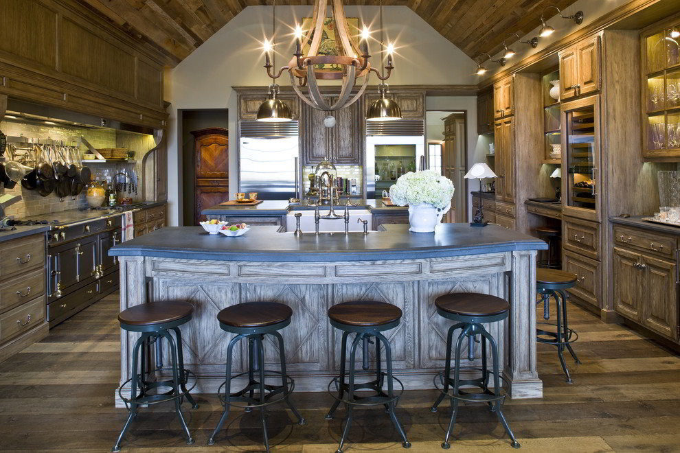 Cette image montre une grande cuisine américaine traditionnelle en U et bois vieilli avec un placard avec porte à panneau surélevé et îlot.